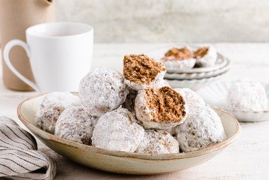 A plate of horchata polvorones coated in sugar next to a hot drink